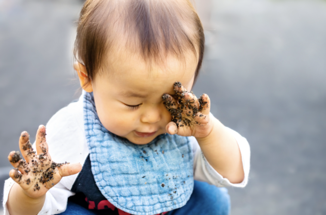 汚れた手で目を擦る幼児
